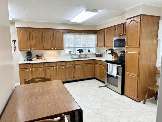 kitchen featuring stainless steel appliances, brown cabinetry, light countertops, and a sink