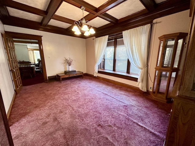 spare room featuring a chandelier, dark colored carpet, coffered ceiling, and beamed ceiling