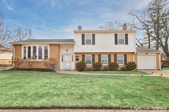 split level home featuring an attached garage, brick siding, driveway, a chimney, and a front yard