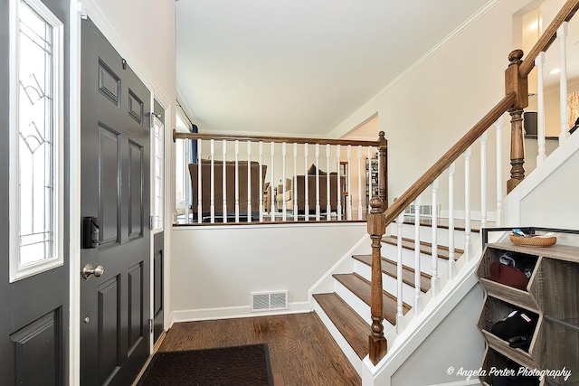 entryway with ornamental molding, wood finished floors, visible vents, and baseboards