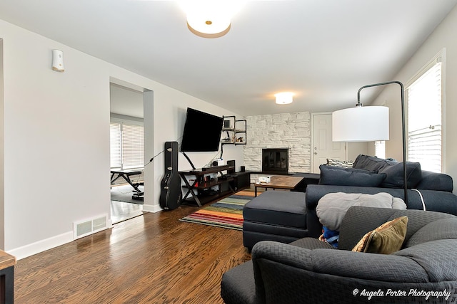 living room with baseboards, a fireplace, visible vents, and dark wood-style flooring