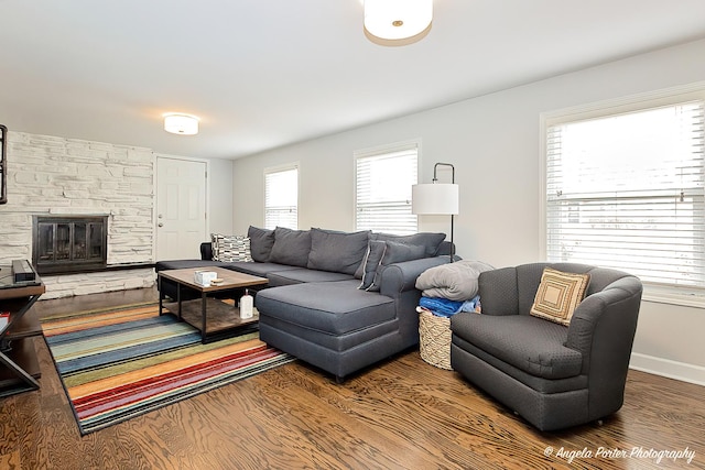 living area featuring a fireplace, baseboards, and wood finished floors