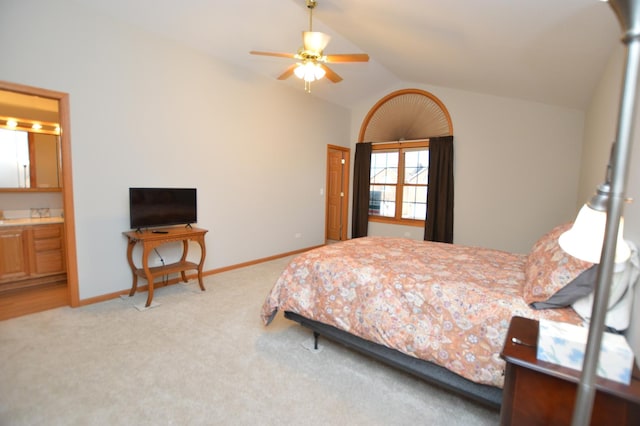 bedroom featuring a ceiling fan, ensuite bath, carpet flooring, baseboards, and vaulted ceiling