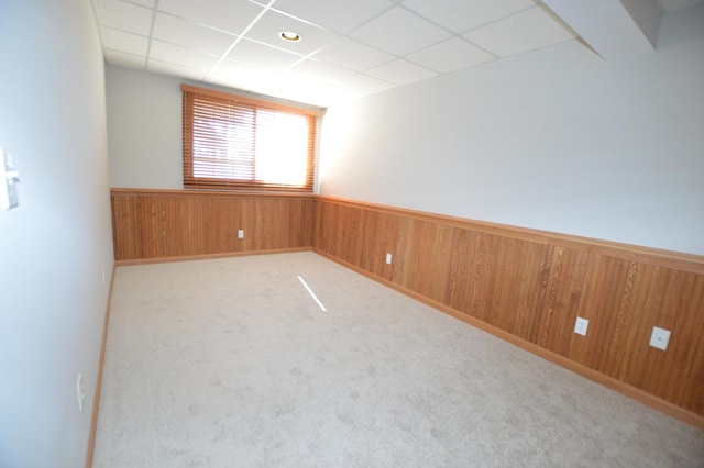 spare room with a paneled ceiling, wood walls, and wainscoting