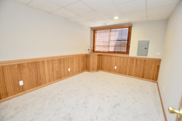 empty room featuring electric panel, a wainscoted wall, carpet floors, and wooden walls