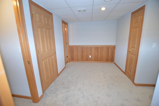 carpeted spare room featuring visible vents, a wainscoted wall, baseboards, a paneled ceiling, and wood walls