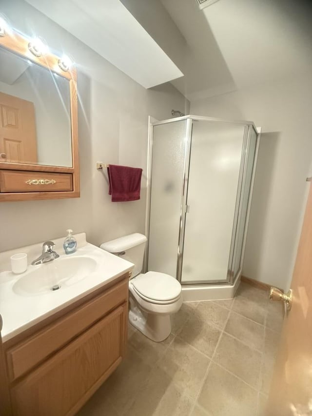 bathroom featuring tile patterned flooring, a shower stall, vanity, and toilet