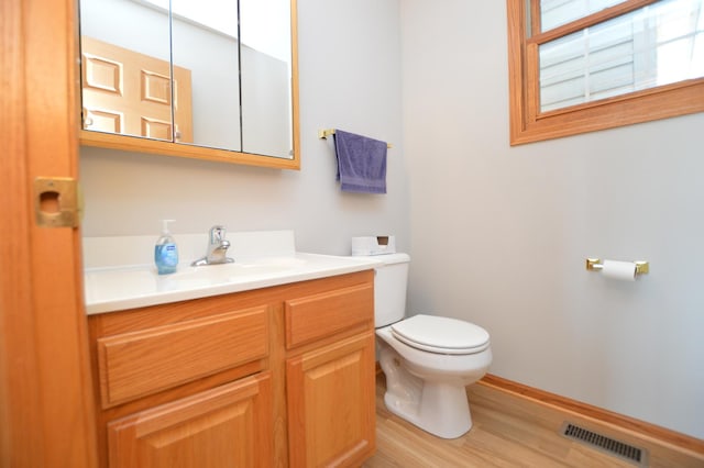 bathroom with visible vents, toilet, wood finished floors, baseboards, and vanity