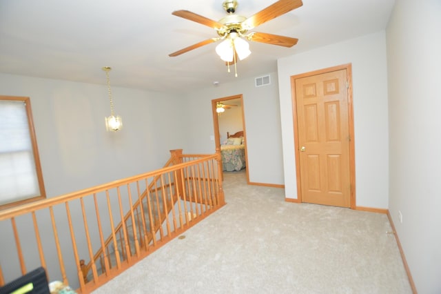 hallway featuring an upstairs landing, visible vents, baseboards, and carpet