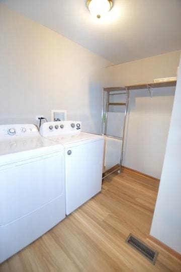 laundry area with light wood-style floors, visible vents, separate washer and dryer, and laundry area