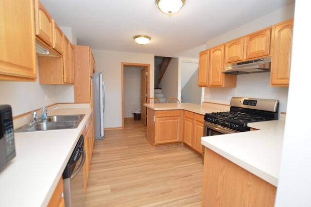 kitchen featuring under cabinet range hood, a sink, light wood-style floors, appliances with stainless steel finishes, and a peninsula