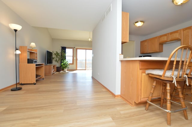 kitchen featuring visible vents, baseboards, open floor plan, light countertops, and light wood-style floors