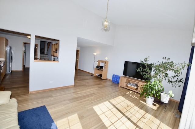 living room featuring wood finished floors, baseboards, and high vaulted ceiling