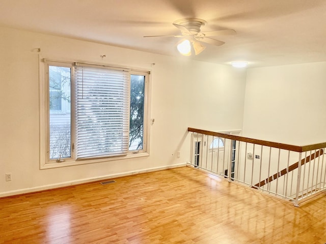 unfurnished room featuring baseboards, wood finished floors, visible vents, and a ceiling fan