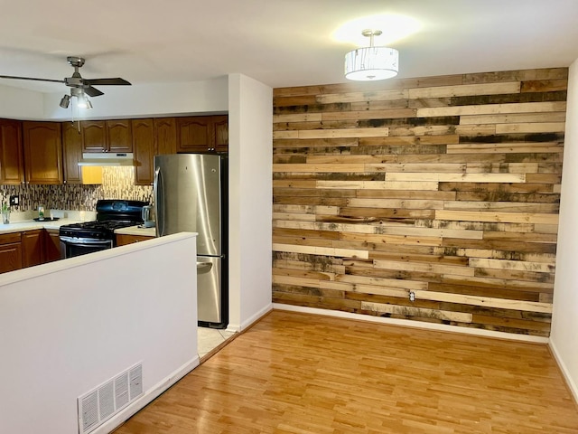 kitchen with visible vents, freestanding refrigerator, light wood-style floors, light countertops, and black range with gas cooktop