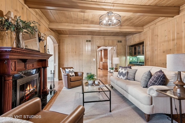 living area featuring arched walkways, wood ceiling, wood finished floors, beam ceiling, and a high end fireplace