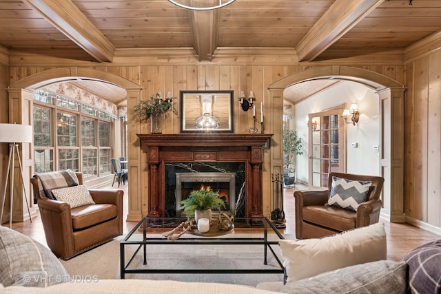 living area with wooden ceiling, arched walkways, beamed ceiling, and a high end fireplace