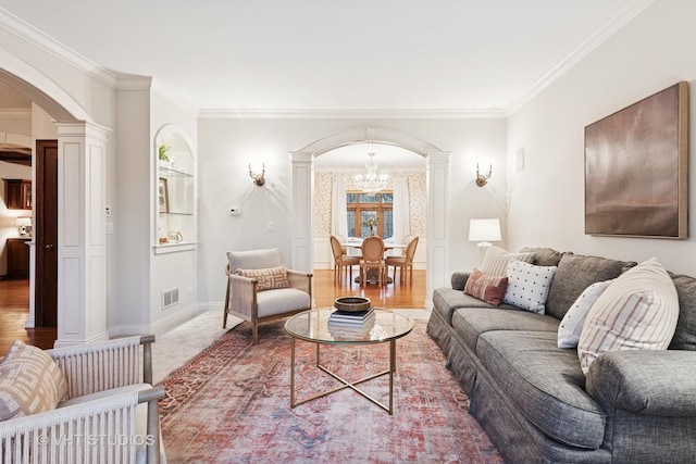 living area featuring arched walkways, ornamental molding, decorative columns, and visible vents