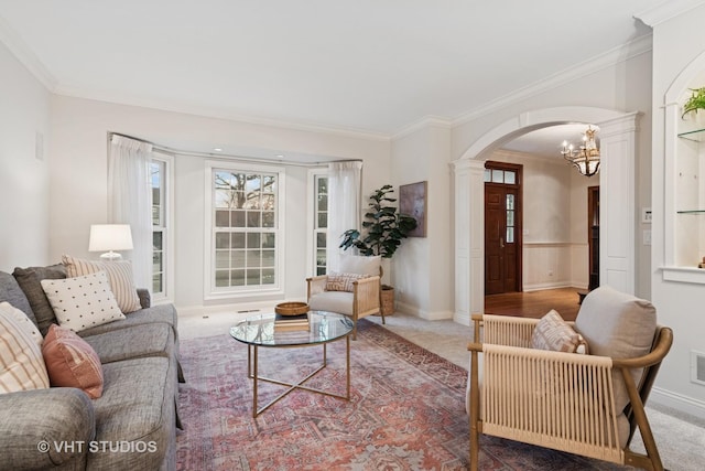 carpeted living room featuring decorative columns, visible vents, arched walkways, ornamental molding, and a notable chandelier