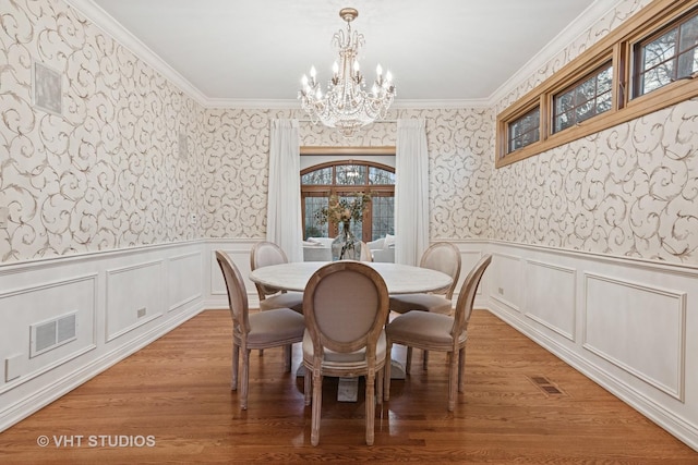 dining room featuring wallpapered walls, ornamental molding, and wainscoting