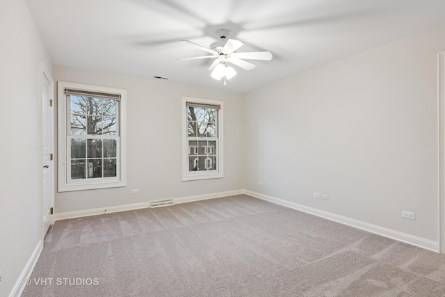 carpeted spare room featuring visible vents, baseboards, and ceiling fan