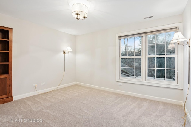 empty room featuring carpet, visible vents, and baseboards