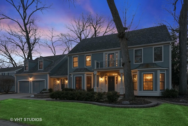 view of front of house featuring driveway, a balcony, an attached garage, and a lawn