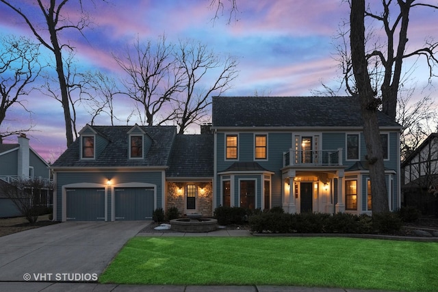 view of front of house featuring a yard, driveway, an attached garage, and a balcony