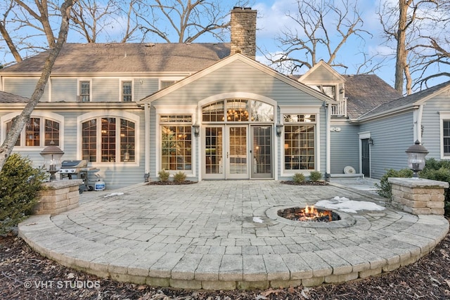 rear view of house with an outdoor fire pit, a chimney, french doors, and a patio