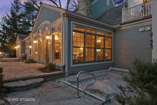 exterior space featuring a balcony, a chimney, and a patio