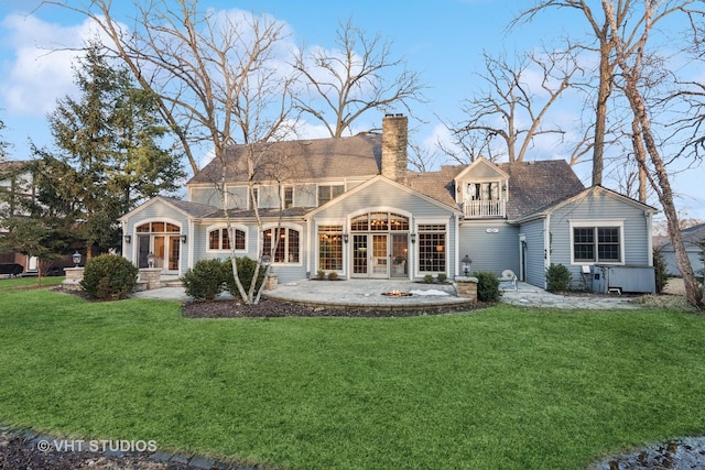 back of house featuring a yard, a chimney, a patio area, and a balcony