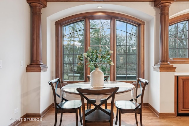 dining room with a wealth of natural light, light wood finished floors, and ornate columns