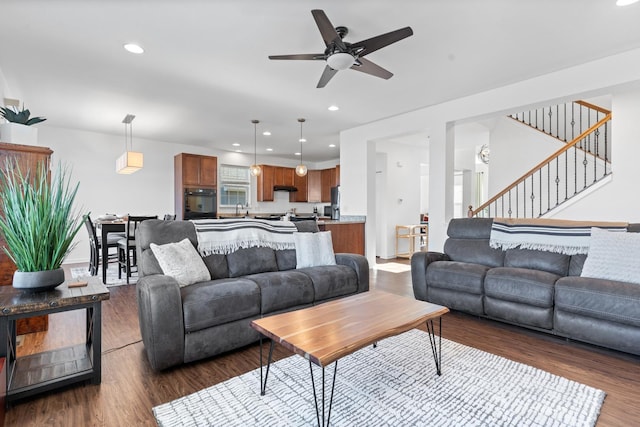 living room featuring a ceiling fan, recessed lighting, dark wood finished floors, and stairs