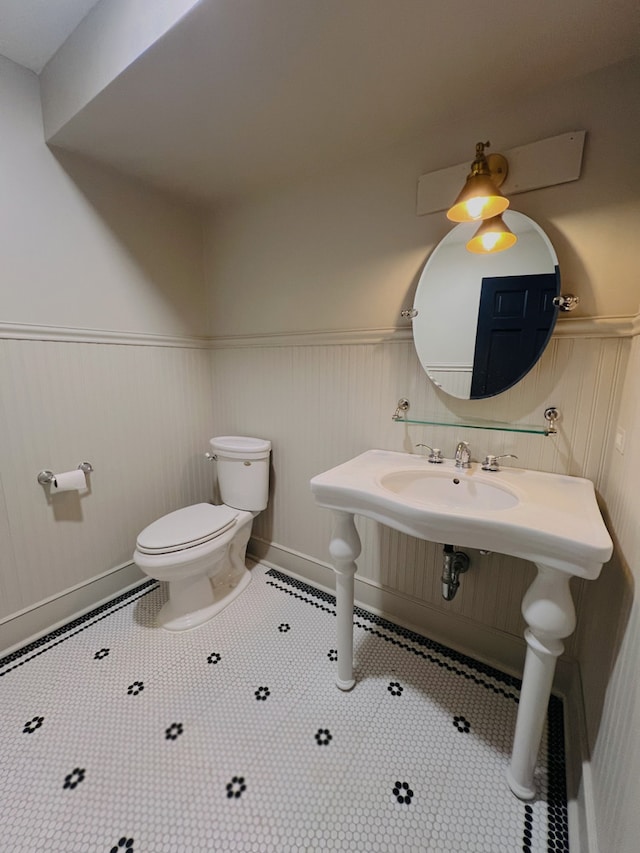 bathroom with a wainscoted wall, tile patterned flooring, and toilet