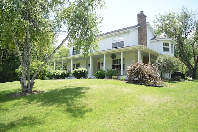 farmhouse inspired home featuring a front yard, covered porch, and a chimney