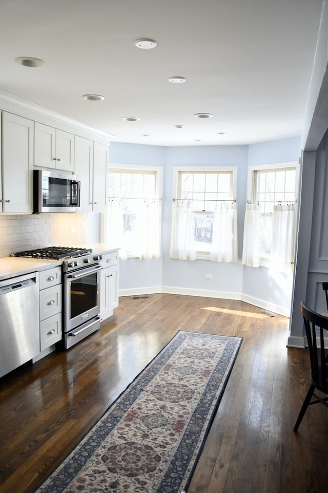 kitchen featuring white cabinets, decorative backsplash, stainless steel appliances, and light countertops