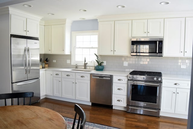 kitchen featuring stainless steel appliances, light countertops, a sink, and white cabinetry