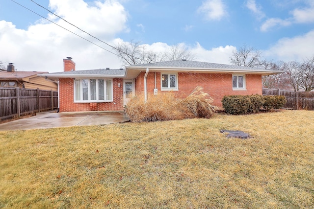 back of house with a yard, a fenced backyard, a chimney, a patio area, and brick siding