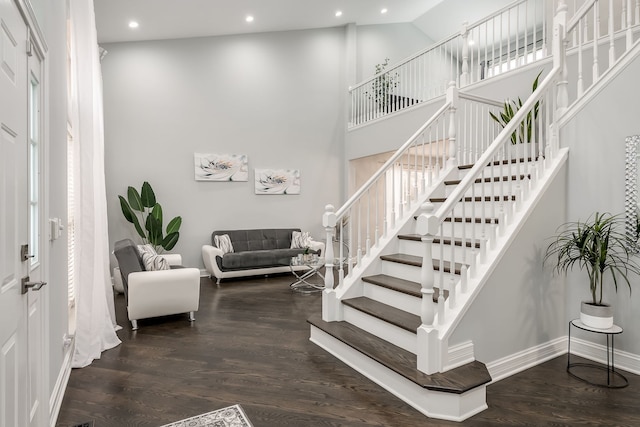 foyer entrance with dark wood finished floors, recessed lighting, a towering ceiling, baseboards, and stairs