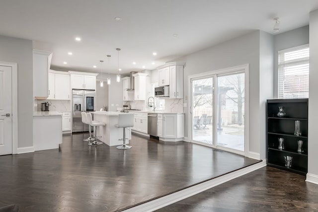 kitchen with pendant lighting, light countertops, appliances with stainless steel finishes, white cabinets, and a kitchen island