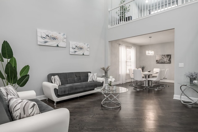 living room featuring dark wood finished floors, a towering ceiling, and baseboards