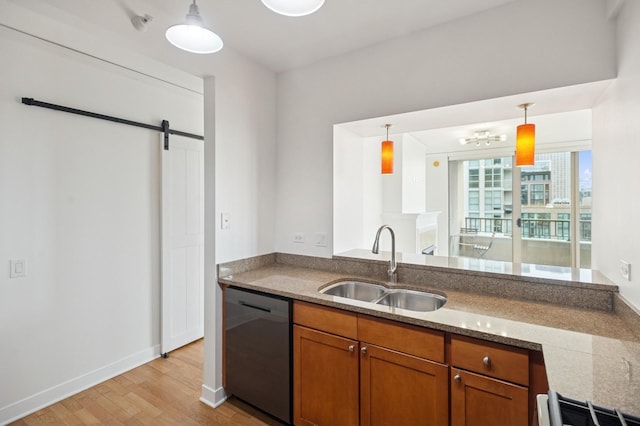 kitchen featuring brown cabinets, a barn door, a sink, light wood-type flooring, and dishwasher