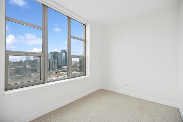 carpeted spare room featuring baseboards and a city view