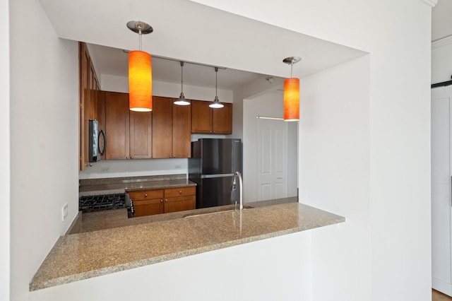 kitchen featuring decorative light fixtures, a sink, a peninsula, and black appliances