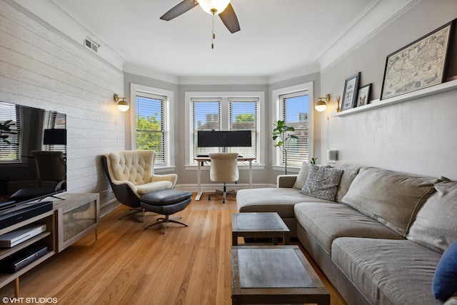 living area with light wood-style floors, visible vents, ornamental molding, and ceiling fan