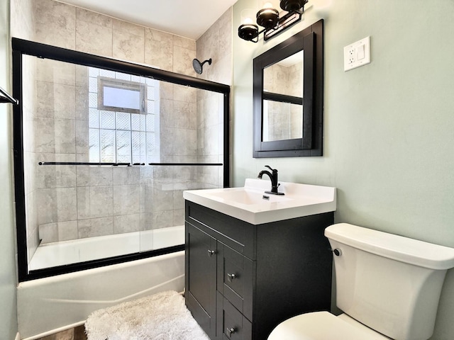 full bathroom with combined bath / shower with glass door, vanity, and toilet