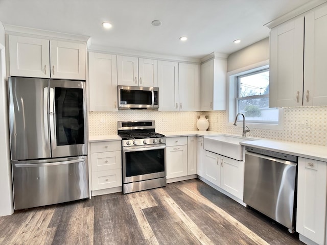 kitchen featuring dark wood-style floors, stainless steel appliances, light countertops, white cabinets, and a sink