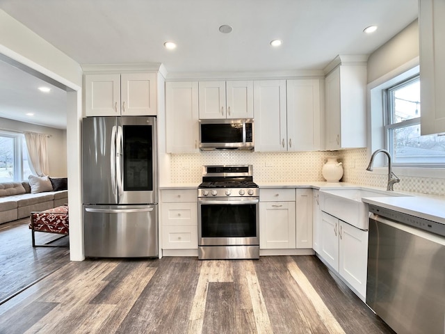 kitchen featuring dark wood-style floors, stainless steel appliances, light countertops, white cabinetry, and a sink