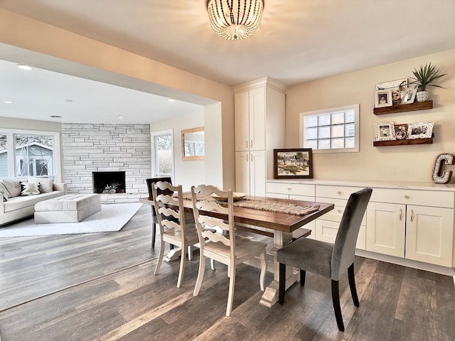 dining room with recessed lighting, dark wood finished floors, and a stone fireplace