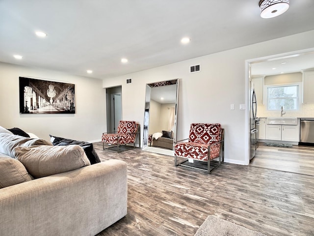 living area featuring baseboards, visible vents, wood finished floors, and recessed lighting